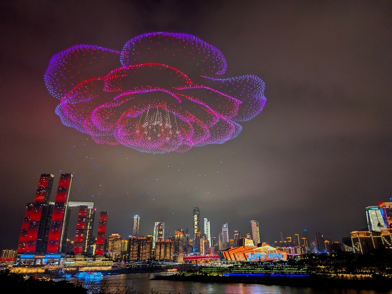 Drone light show forming a glowing flower above the Chongqing skyline at night